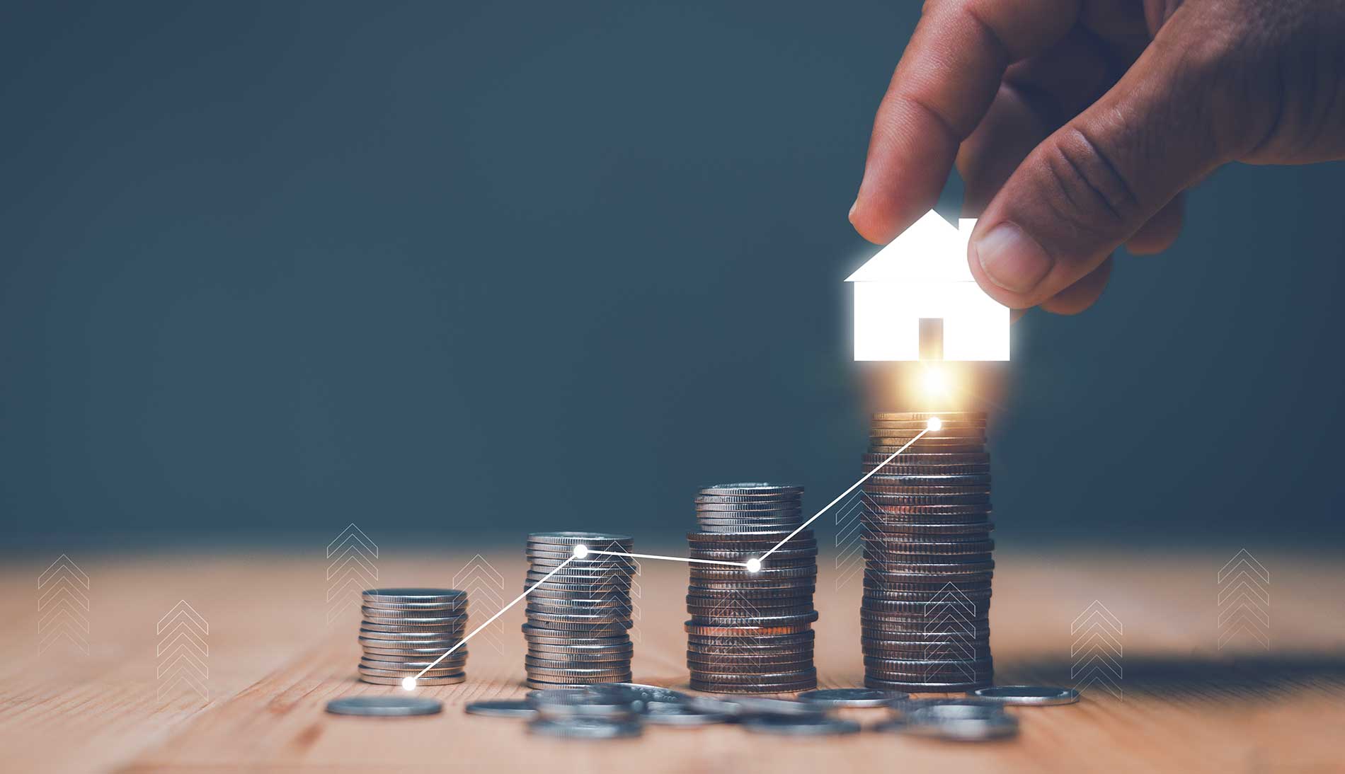 Investition für Immobilienkonzept, die Hand eines Geschäftsmannes legt das Haussymbol auf den Münzstapel und die fortschreitende Grafik
